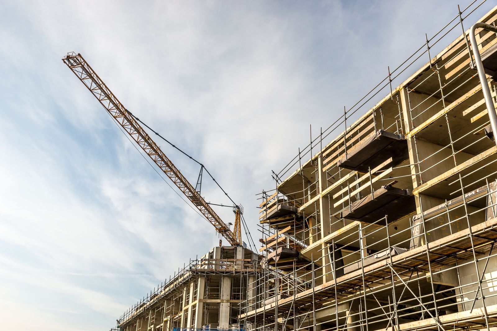A building under construction with a tower crane against the sky